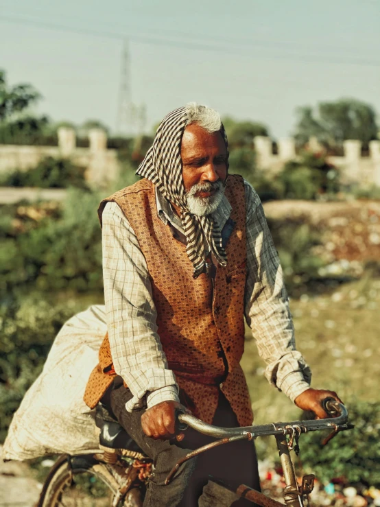 a man in plaid clothes and bandana holds a bicycle