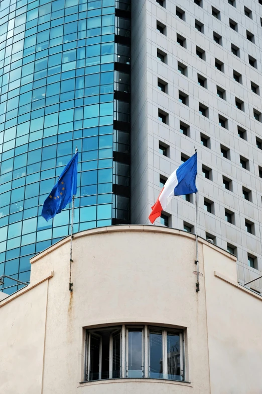 a corner of an urban building with an italian flag hanging off it's side