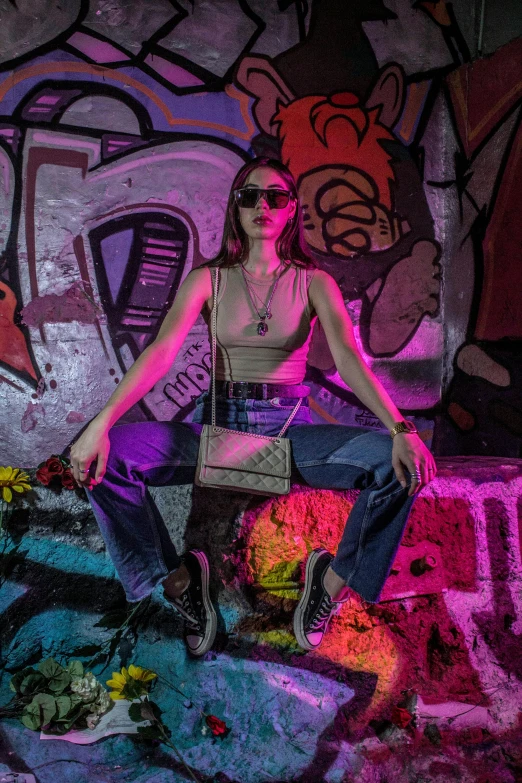 a woman sitting on a rock while wearing sunglasses