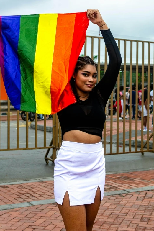 a woman is holding up a rainbow flag