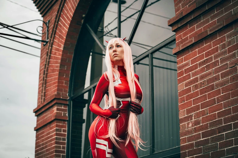 woman in red catsuit and horns posing near building