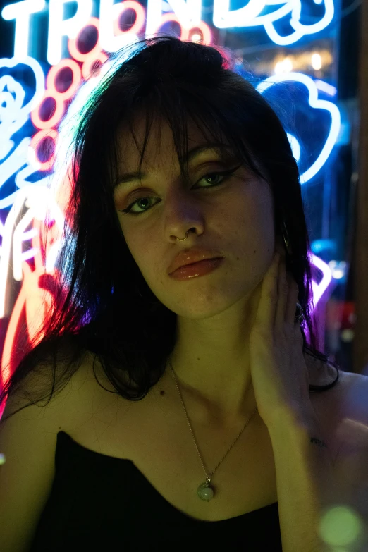 a woman posing in front of a neon sign