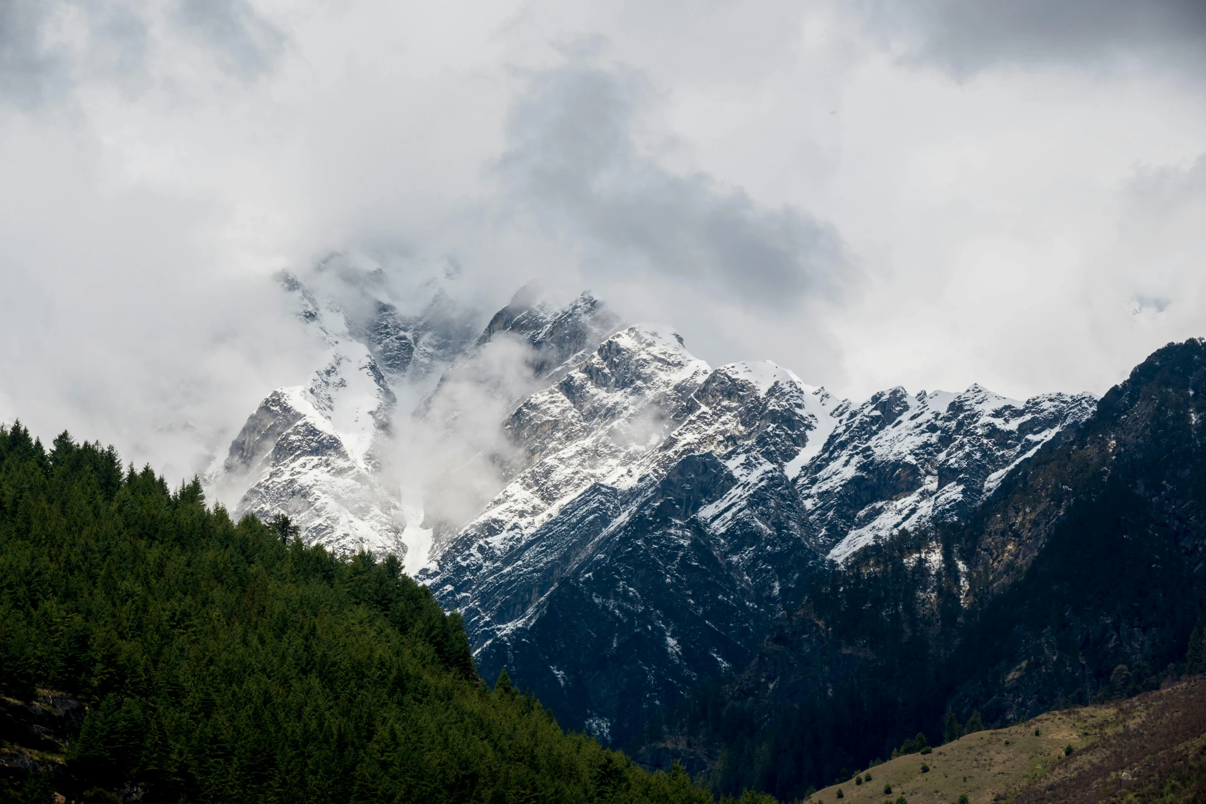 a mountain range covered in snow and clouds