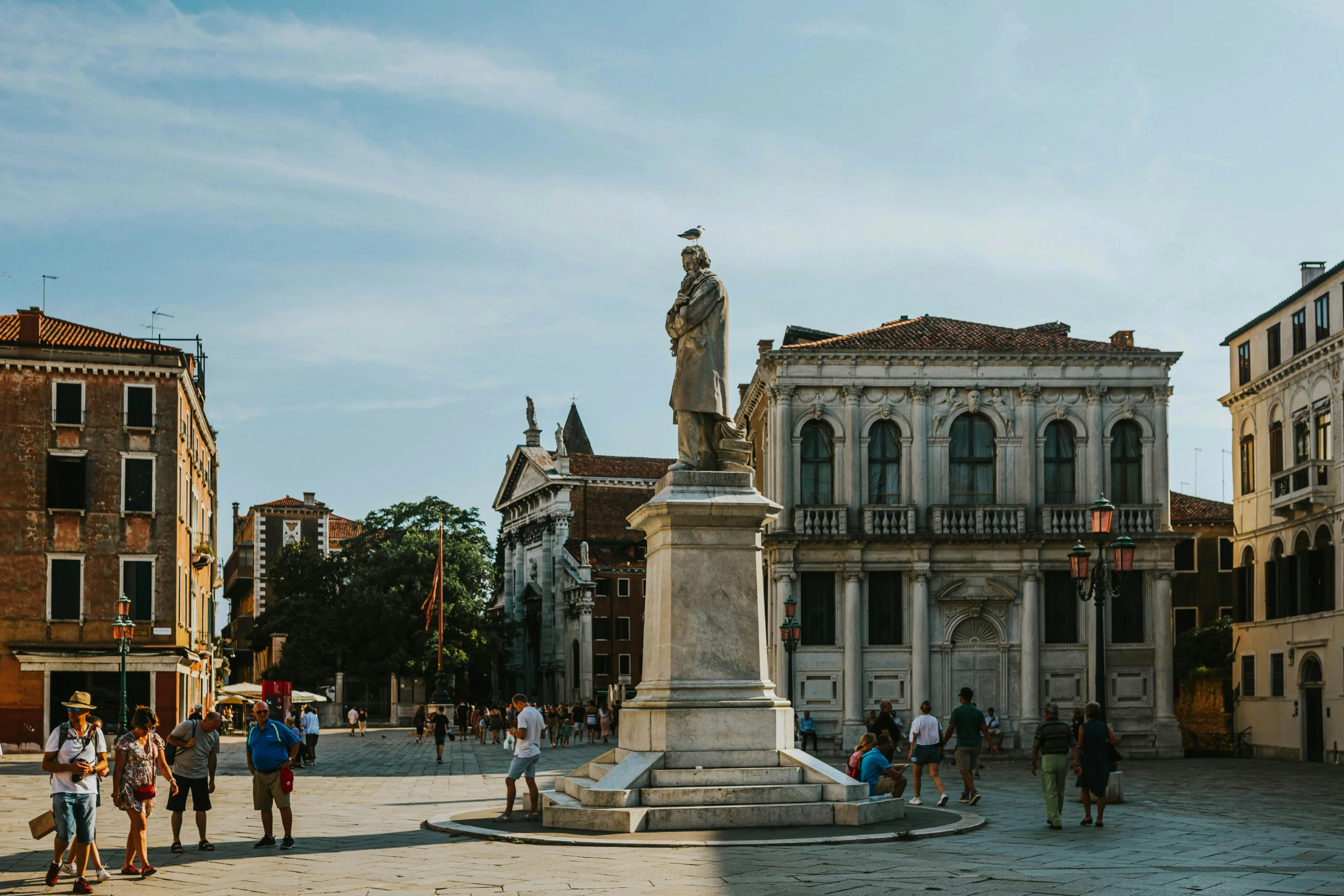 people walking around in front of a building with statues in the middle