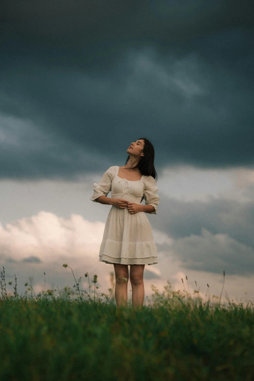 a woman standing alone against a cloudy sky