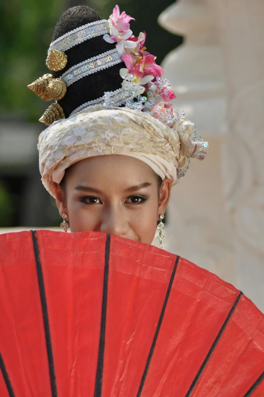 a woman with a fan wearing a black and white hat