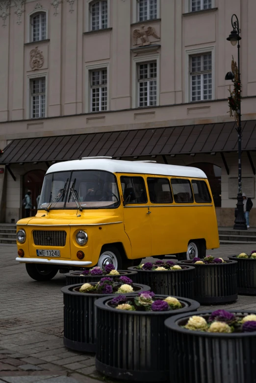 the old yellow bus is parked by some flowers