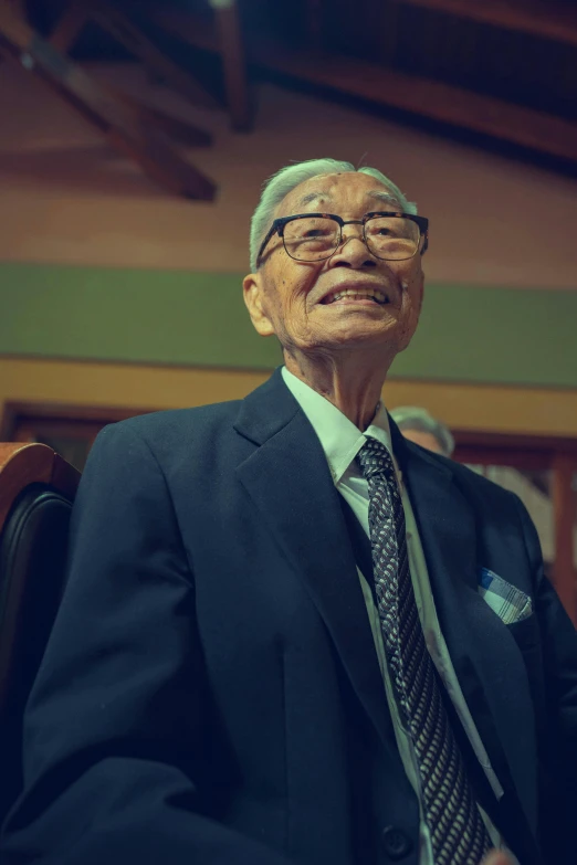 an older man sitting in a chair with a suit on