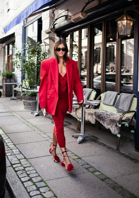 a woman walks down the sidewalk with red shoes