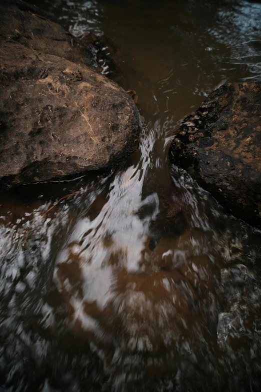 water coming out of a stream into large boulders