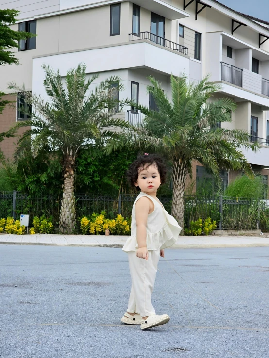 a girl wearing a white outfit poses in front of a building