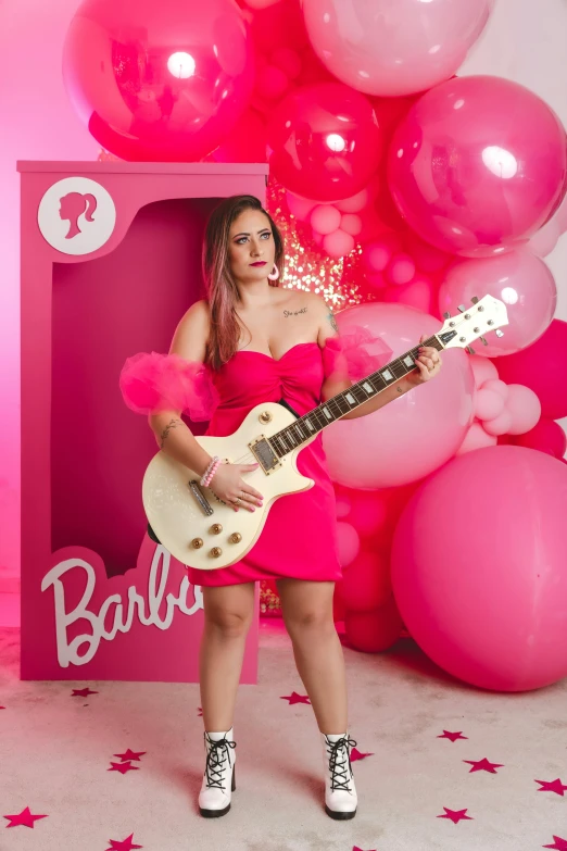 woman in pink dress standing with guitar posing for a pograph