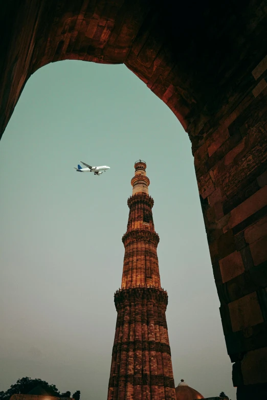 an airplane is flying over a red tower