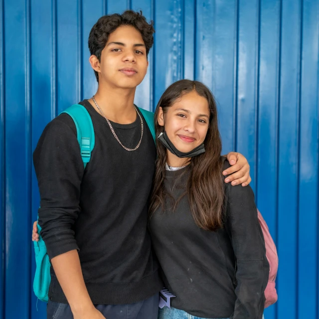 two s are posing in front of a blue wall