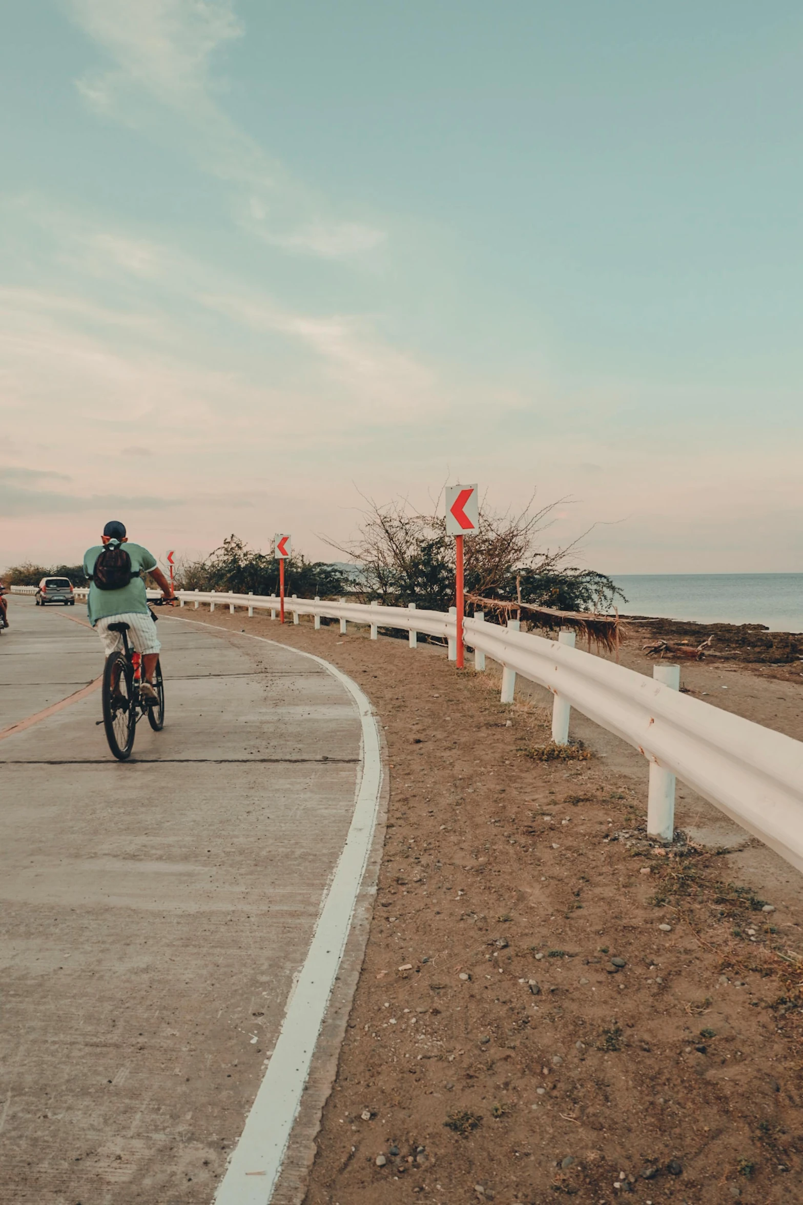 a man rides a bike next to some beach front traffic