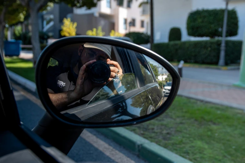 a man takes a picture in the side mirror of a car