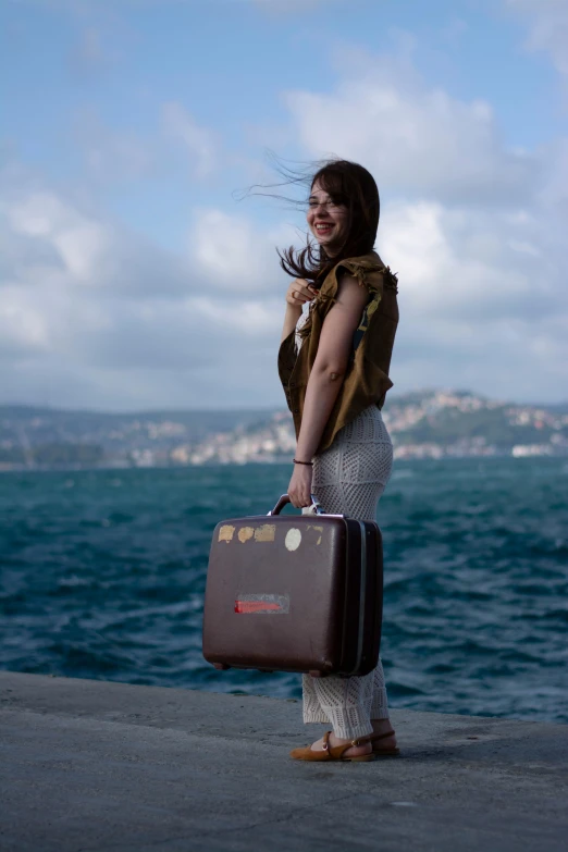 a woman holding a suitcase near the ocean
