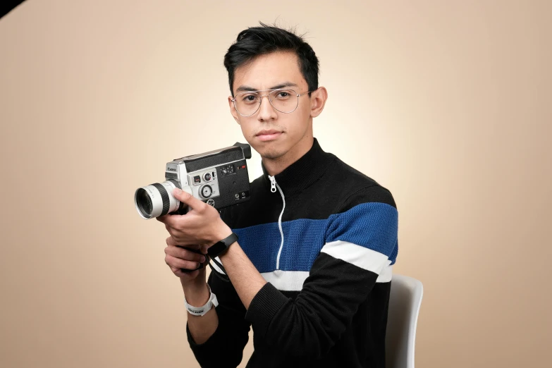 an asian man is holding a camera with earphones on
