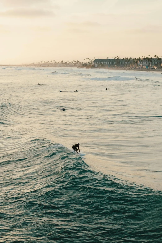 a surfer riding the surfboard in the ocean at sunset