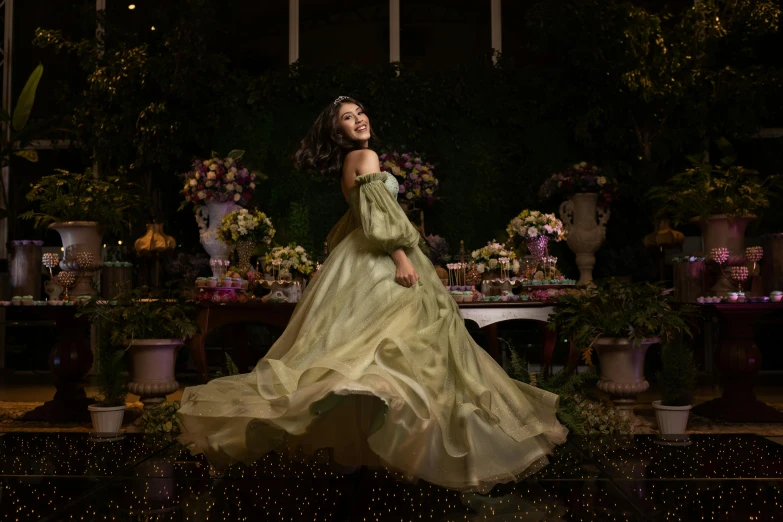 a woman in a green dress is standing by some flowers