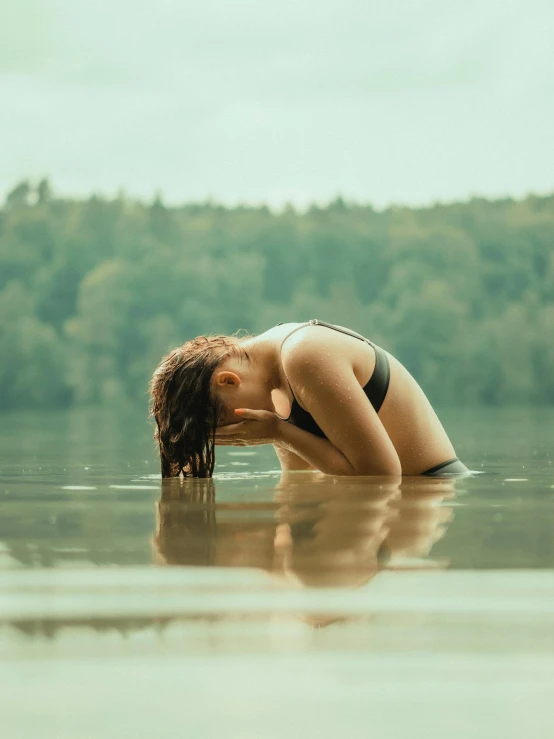 a woman is bent over in a lake