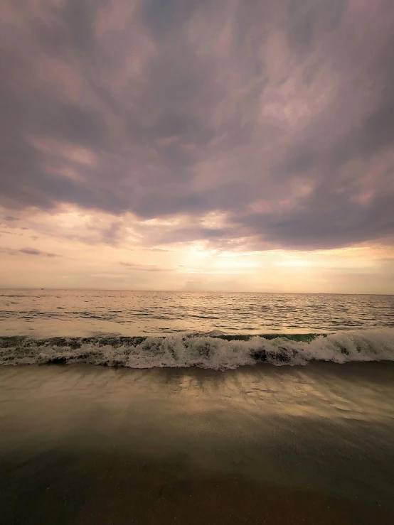 some water waves and a cloudy sky on a beach