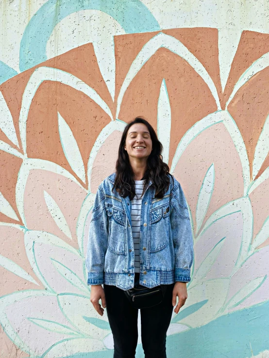 a smiling woman in front of a painted wall