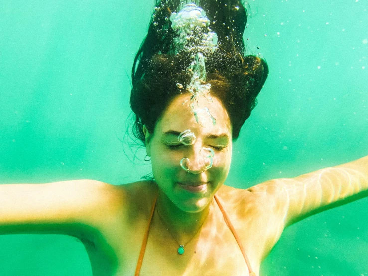 a woman swims under the water wearing a bikini