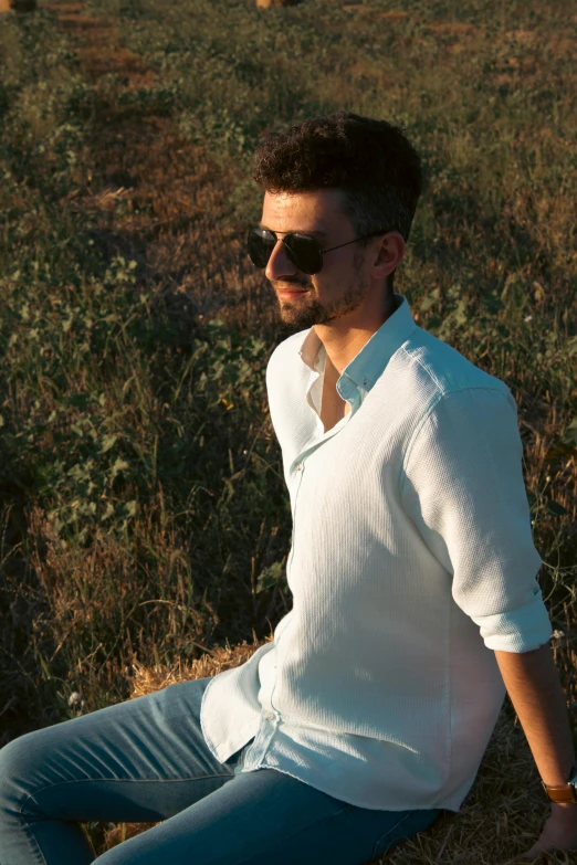 a man wearing sunglasses sits in the grass