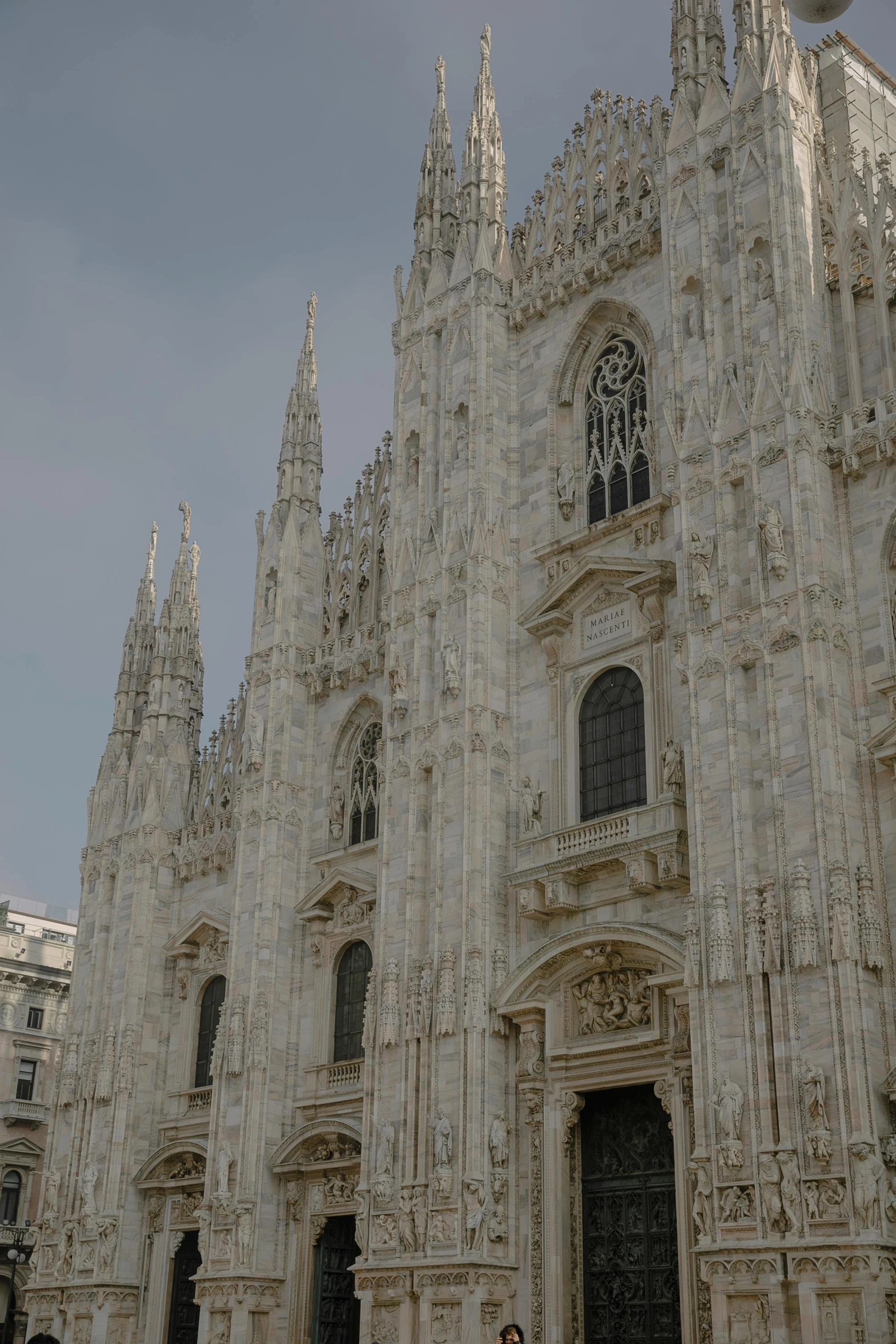 a cathedral with towers and a woman standing next to the doors