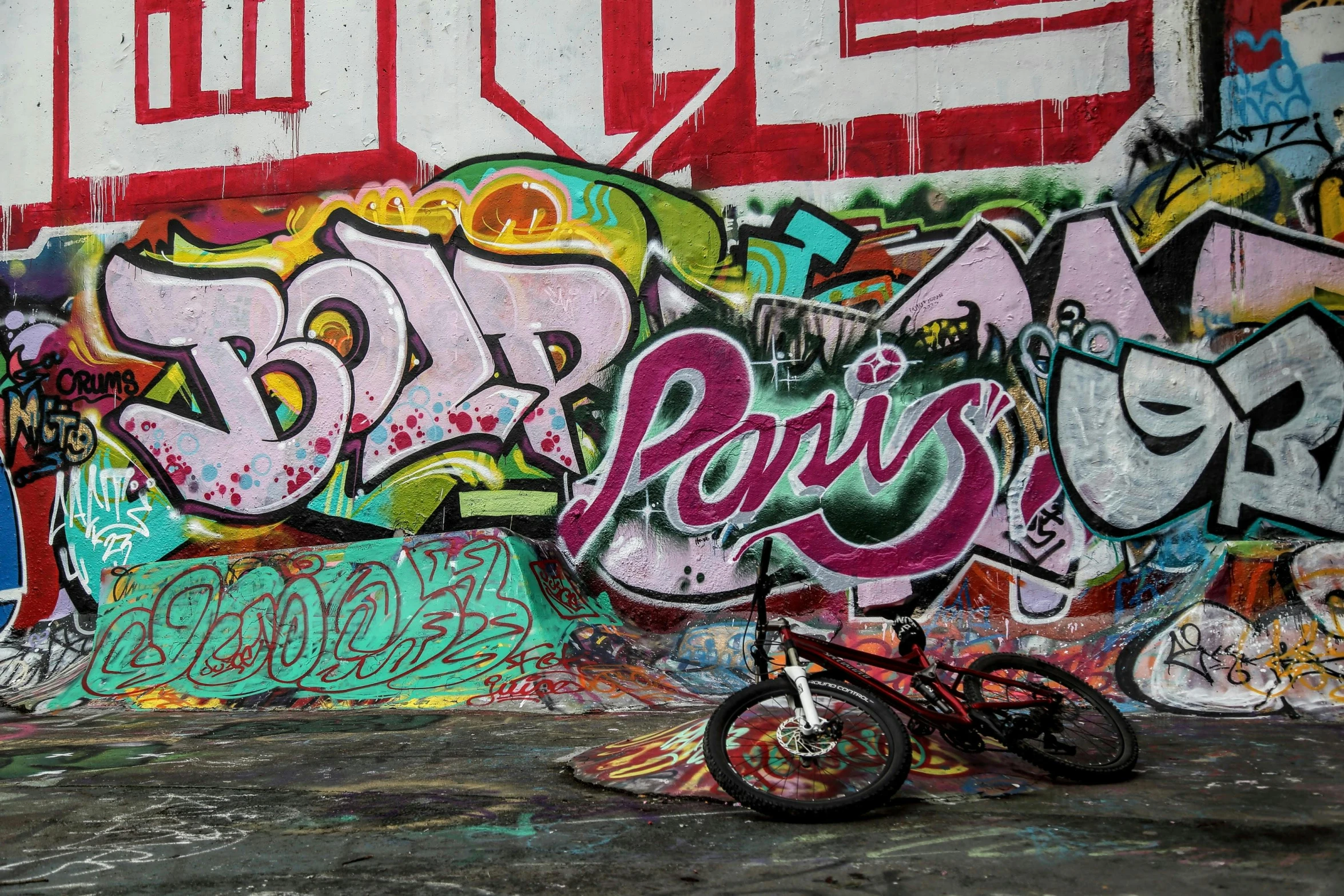 a bicycle parked against the wall with lots of colorful graffiti on it