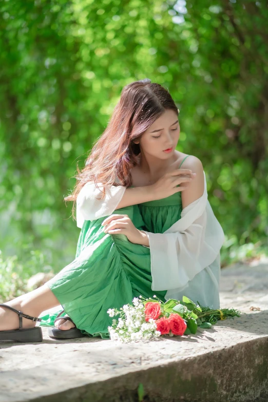 woman in a green dress and a white robe seated on a cement step