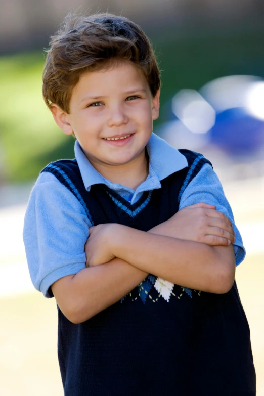 a smiling boy wearing a polo shirt and blue vest