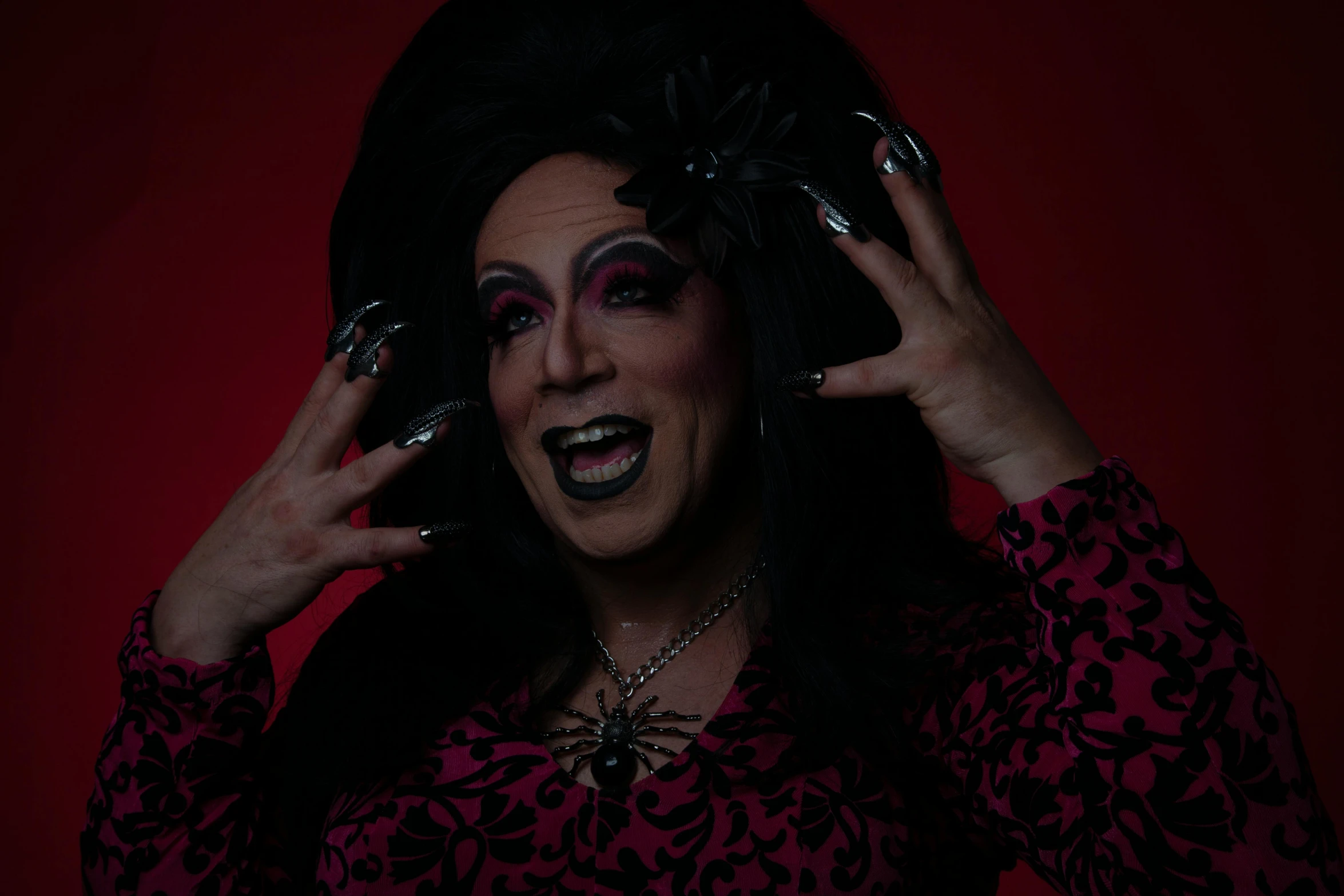 a woman in a black wig holding her hands up to her face