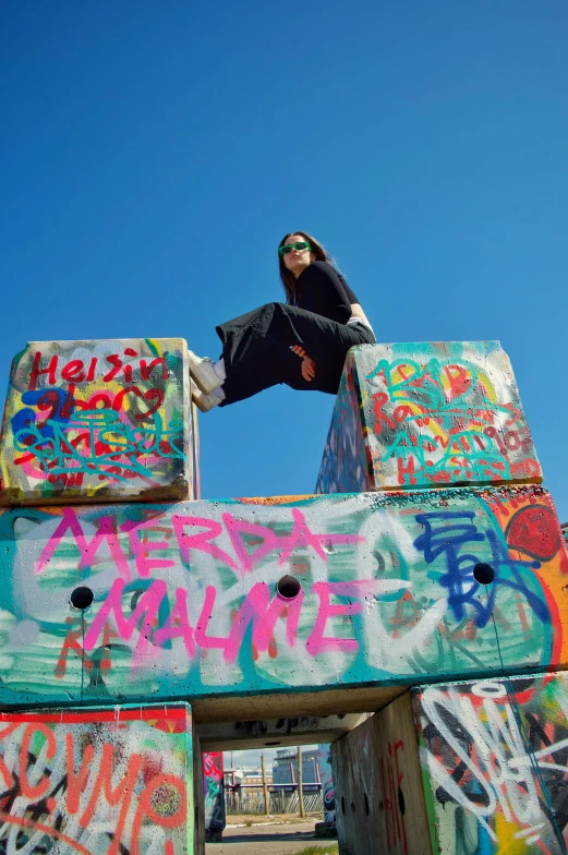 a boy standing on top of a big wooden box covered in graffiti