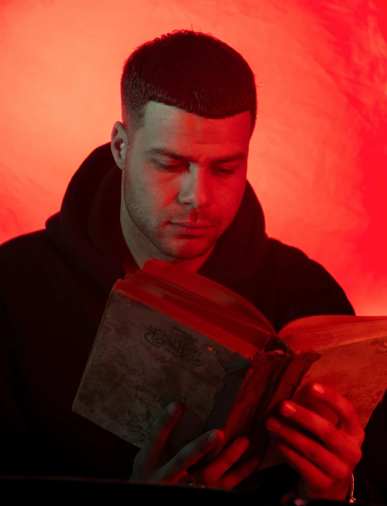 a man is holding an open book against a red background