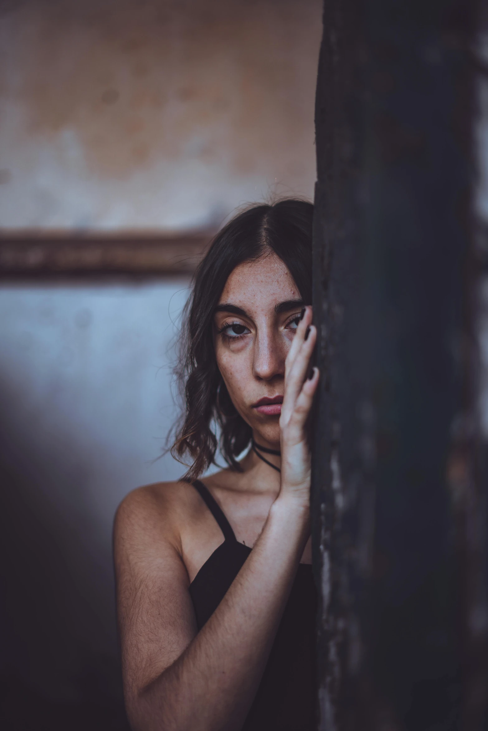 a woman in black top leaning against wall