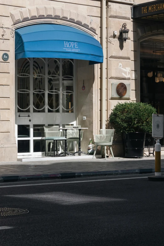 a couple of tables and chairs sitting under a blue umbrella