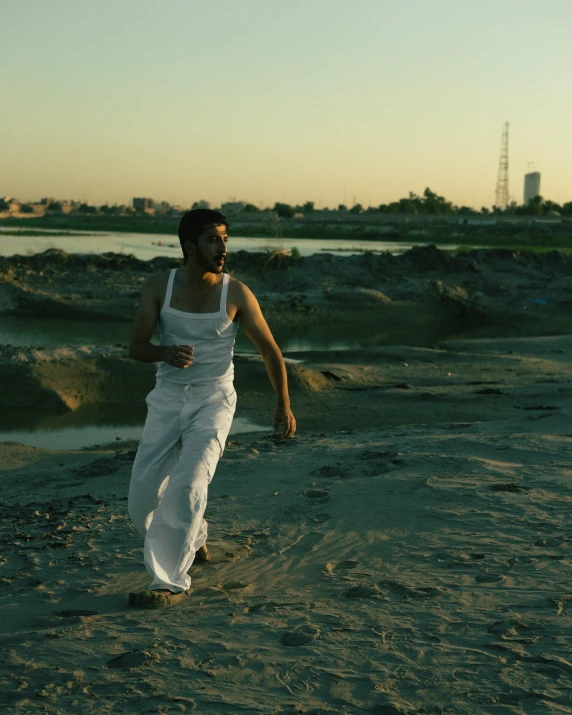 a young man running on the beach toward the camera