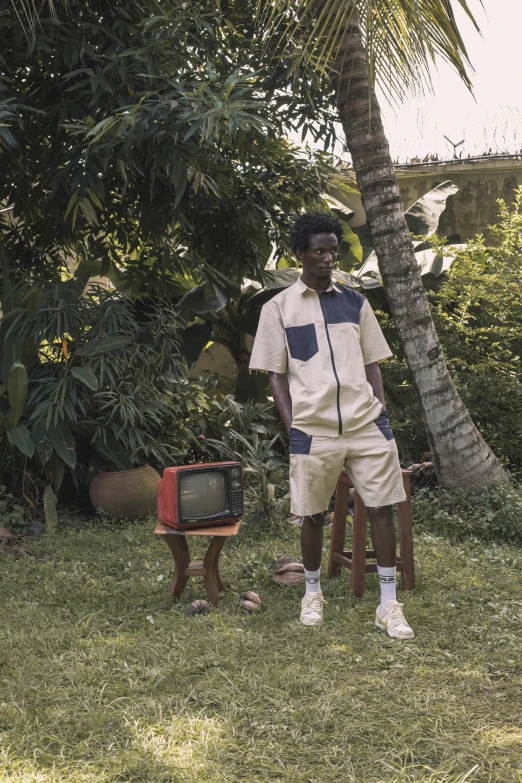 a young person stands on the grass with an old television