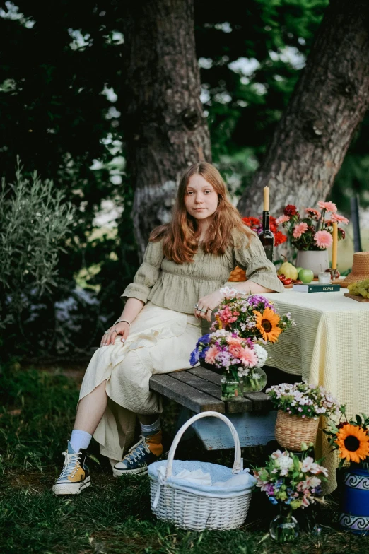 a beautiful young woman sitting next to a table filled with flowers