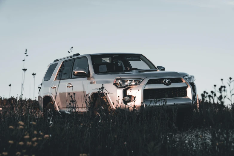 a white car parked next to the ocean in an empty field