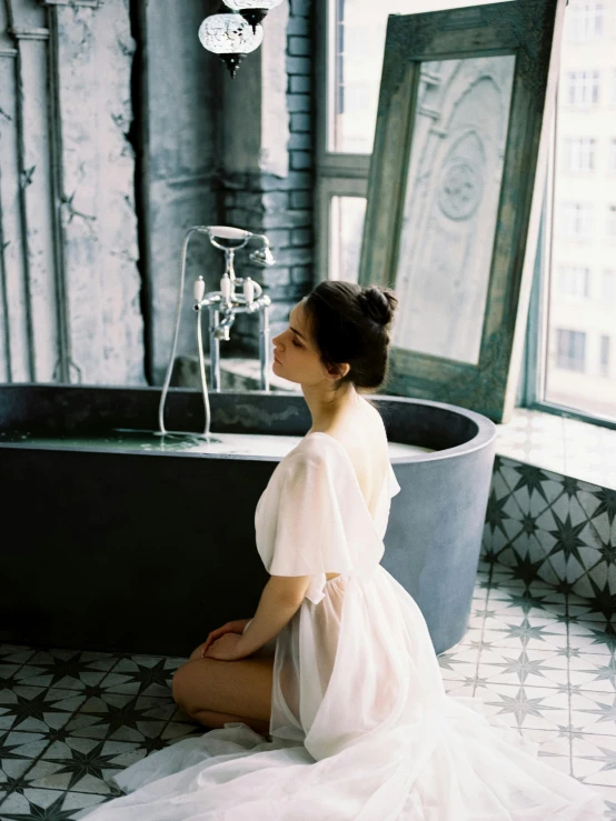a woman in a white dress sitting in front of a bathtub