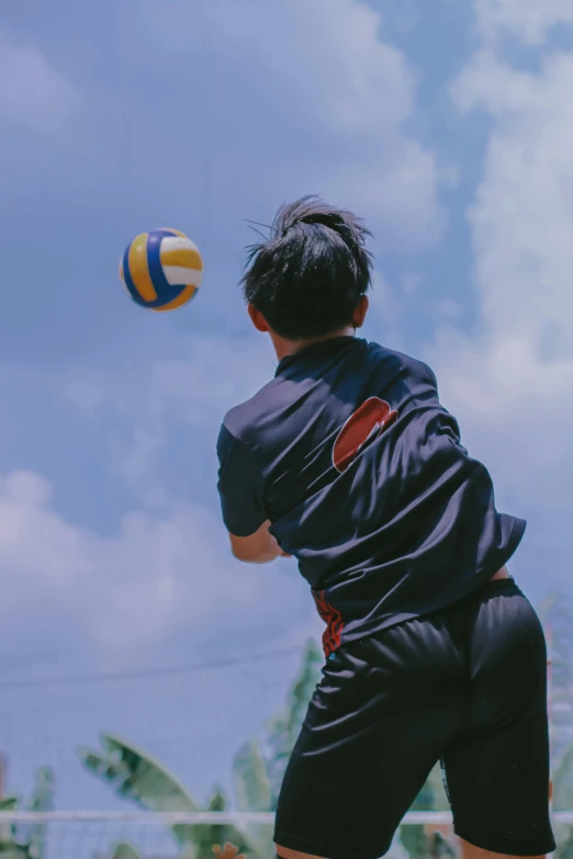 a boy hitting a volleyball on a sunny day