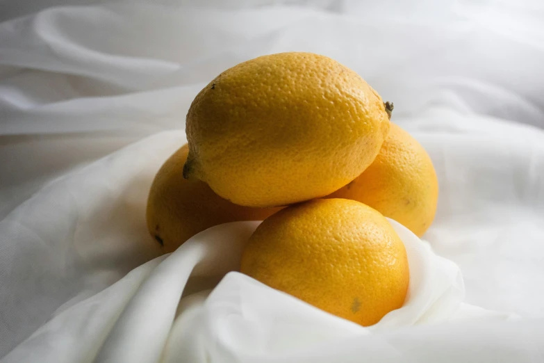 three ripe oranges sitting next to each other on a cloth