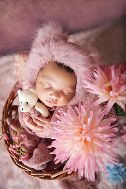 a baby wearing a pink fur coat sleeping on a blanket with a stuffed animal