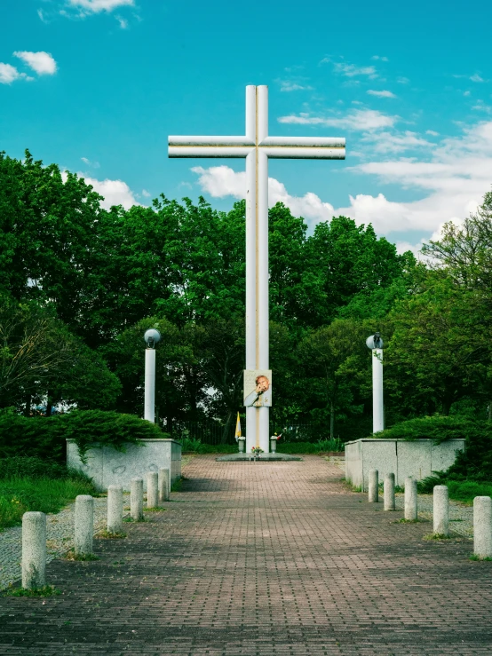 a large white cross in front of green trees