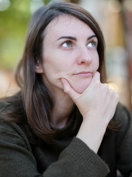 woman looking down with her hands on her chin