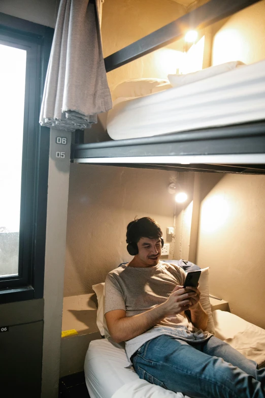 a man sits on the edge of his bunk bed