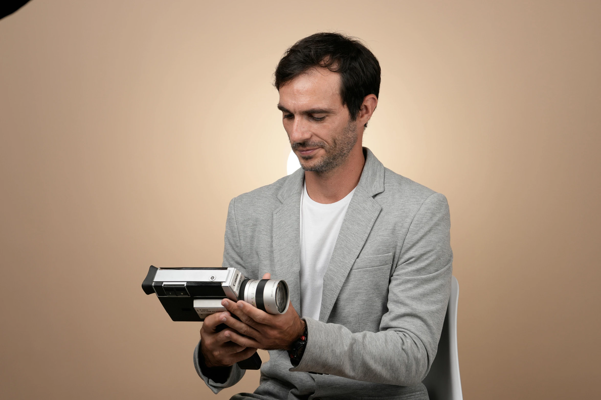 a man wearing a grey suit with an old fashioned camera